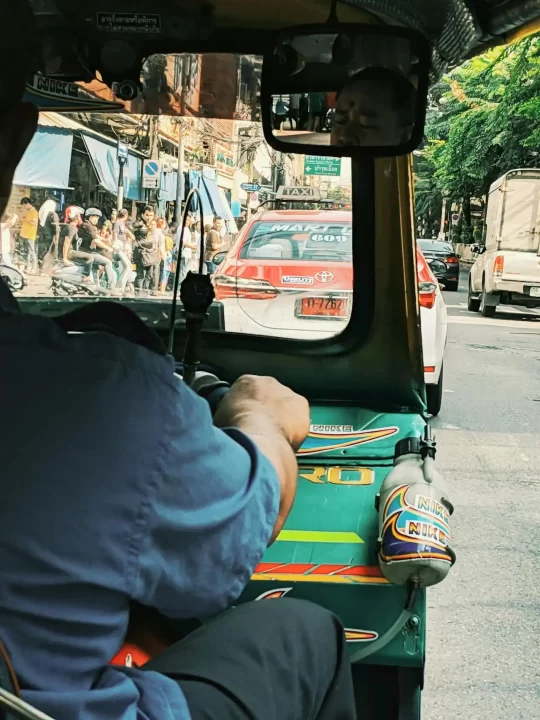 Navigating the thai market - operational insights for foreign investors - cnb trustee, your trusted partner in legacy advisory and will writing services. View from inside a traditional tuk-tuk driving behind a red taxi in bangkok, symbolizing the fast-paced and complex regulatory environment of thailand's business sector.