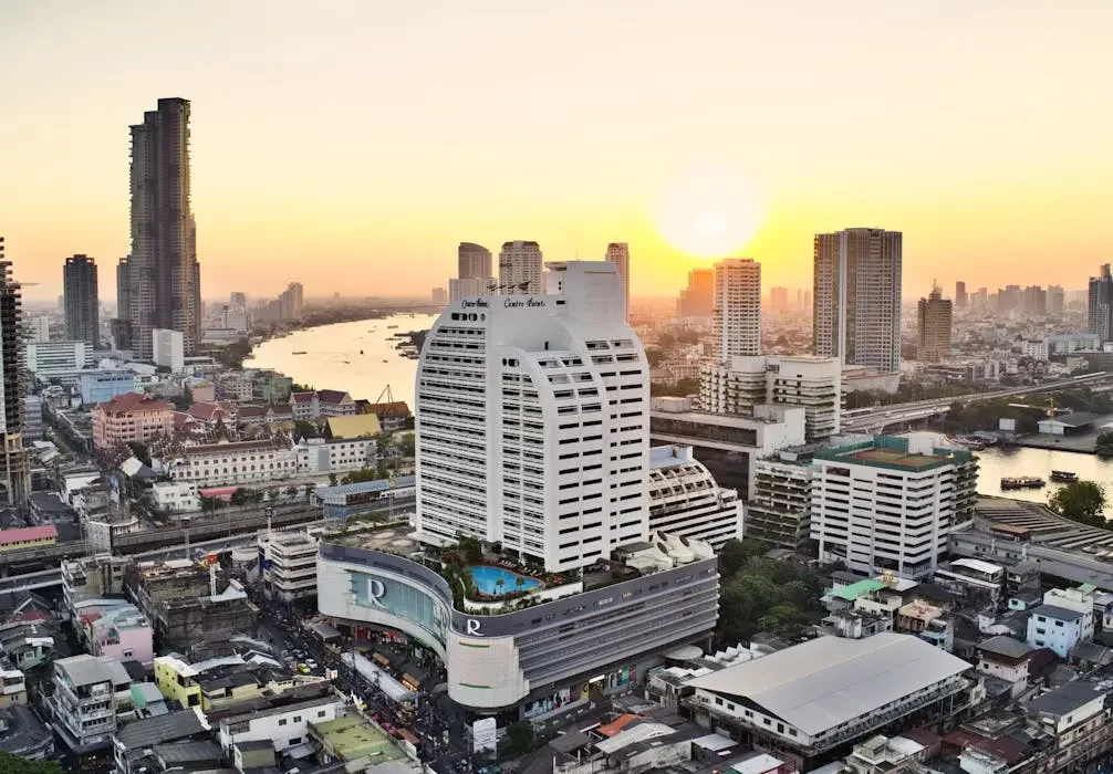 วิวแม่น้ำเจ้าพระยาและตึกระฟ้าในกรุงเทพฯ ยามเย็น แสดงถึงศูนย์กลางธุรกิจและความมั่งคั่งของไทย